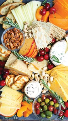 an assortment of cheeses, crackers, nuts and fruit on a platter