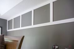 a room with gray walls and white trim on the wall, along with a wooden bench