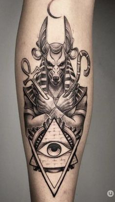 an egyptian tattoo on the leg with an all seeing eye and an evil demon sitting in front of it