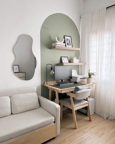 a white couch sitting in front of a computer on top of a wooden desk next to a window