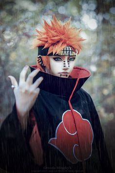 a man with orange hair and makeup holding his hand up to the camera