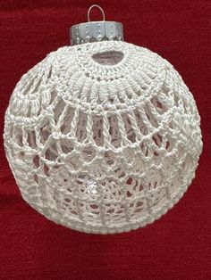 a white crocheted ornament hanging on a red background