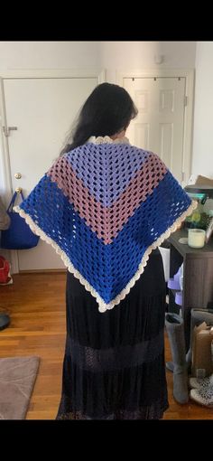 a woman standing in a room with a crocheted shawl on her back