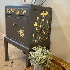 a black dresser with yellow honeycombs painted on it and a potted plant next to it