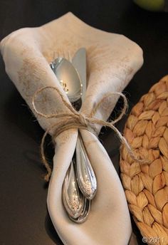 an image of spoons and napkins wrapped in twine on top of a table