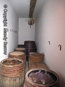 several wooden barrels are lined up in a narrow room with white walls and ceiling fan