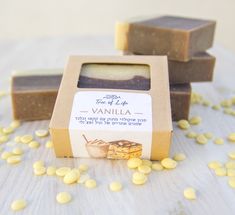 three bars of soap sitting next to each other on top of a wooden table covered in yellow seeds