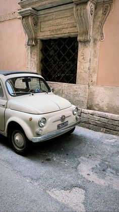 an old white car parked in front of a building