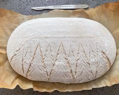 a loaf of bread sitting on top of a piece of paper next to a knife