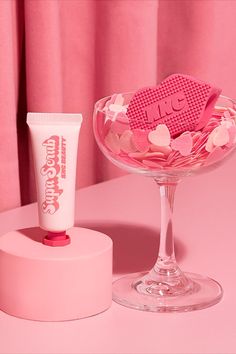 a pink table topped with a glass bowl filled with candy