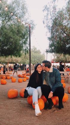 a man and woman sitting on top of pumpkins