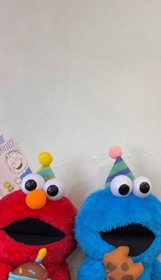 two stuffed animals with birthday hats on sitting next to each other in front of a white wall