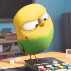 a green bird sitting on top of a remote control