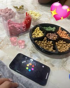 a table topped with lots of food next to a cell phone and cupcakes