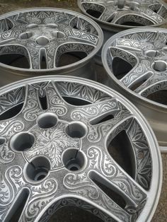 four silver rims with intricate designs on them