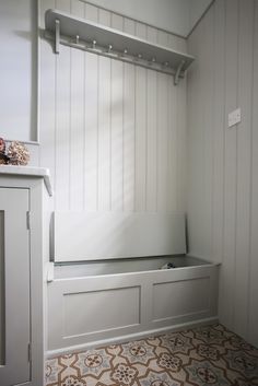 a white bench sitting in the corner of a room next to a cabinet and door