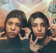 two young women posing for the camera with their hands in front of her face and one pointing