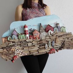 a woman holding up a piece of art made out of driftwood and wood planks