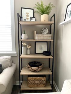 a living room with a white couch and some shelves filled with books, plants and pictures