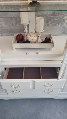 a white dresser with drawers and candles on top