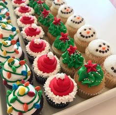 cupcakes decorated with frosting and decorations are lined up on a white tray