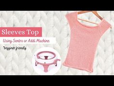 a pink tank top sitting on top of a white rug next to a wooden hanger