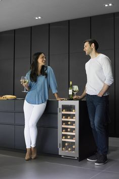 a man and woman standing in front of a wine cooler