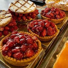 several pies and pastries on display in a store window, with strawberries filling the top