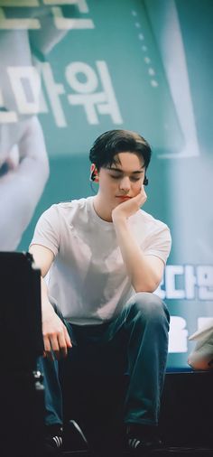 a young man sitting on top of a table next to a laptop computer