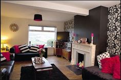 a living room filled with black and white furniture next to a fire place in front of a window