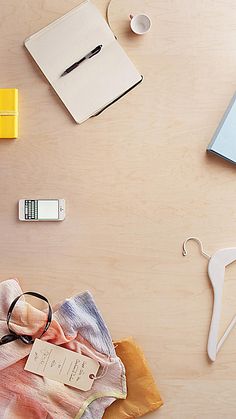 clothes and accessories laid out on a wooden table with clipboards, pens, scissors, paper clips