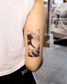 a person with a tattoo on their arm that has a wave in the middle of it