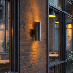 an outdoor wall light on the side of a brick building with windows and tables outside