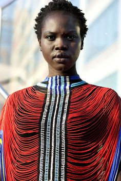 a woman wearing a red and blue dress standing in front of a building with her hands on her hips