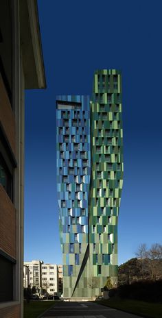 two tall buildings with green and blue squares on the side of them, against a blue sky