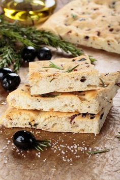 three pieces of crackers with olives and rosemary sprigs next to them