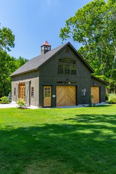 a barn with two garages and a clock tower in the middle of a field