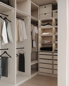 an organized closet with clothes hanging on rails