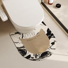 a white toilet sitting on top of a bathroom floor next to a black and white rug