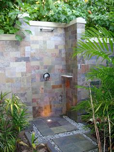 a walk in shower sitting next to a lush green forest filled with trees and plants