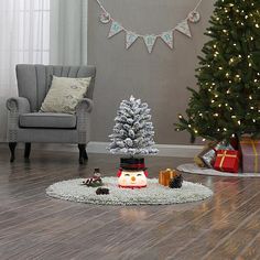 a living room decorated for christmas with a small tree and presents on the floor in front of it