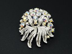 "Coro Aurora Borealis Rhinestone Brooch Silver Tone Rhodium Plated Pin, 1950's Vintage Coro Brooch, Wedding Floral AB Brooch Signed Coro *Description: This beautiful Coro Aurora Borealis clear rhinestone brooch is on a silver rhodium plated metal. The signature on the back of the brooch places this piece of vintage jewelry in the 1950s. It would be a gorgeous brooch to wear to a wedding. It is full of color and sparkle. All rhinestones are in place and everything about this brooch looks like new Silver Sparkling Brooches For Evening, Sparkling Silver Brooches For Evening, Silver Brooches With Sparkling Stones For Evening, Silver Evening Brooches With Sparkling Stones, Silver Costume Jewelry Brooches For Party, Silver Brooches With Sparkling Stones For Party, Glamorous Silver Brooches For Party, Glamorous Silver Bling Brooch, Silver Rhinestone Brooches For Vintage Events