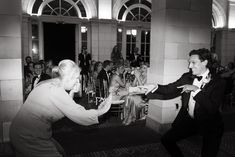 two people in tuxedos are dancing at an event