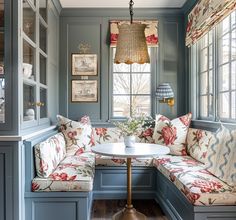 a room with blue walls and floral cushions on the couches in front of a window