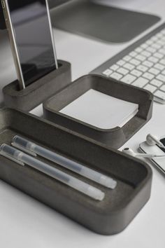 an office desk with a keyboard, cell phone and pen holder on top of it