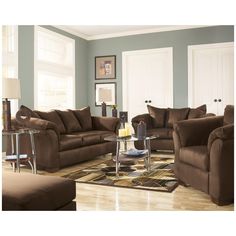 a living room filled with brown furniture and lots of pillows on top of the couches