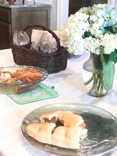 a table topped with pies and flowers on top of a white tablecloth covered table