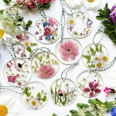 several glass ornaments with flowers and twine around them on a white tablecloth surrounded by daisies