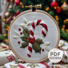 a cross stitch christmas ornament with candy canes and holly