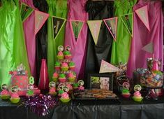 a table topped with lots of pink and green desserts, cupcakes and candy bars